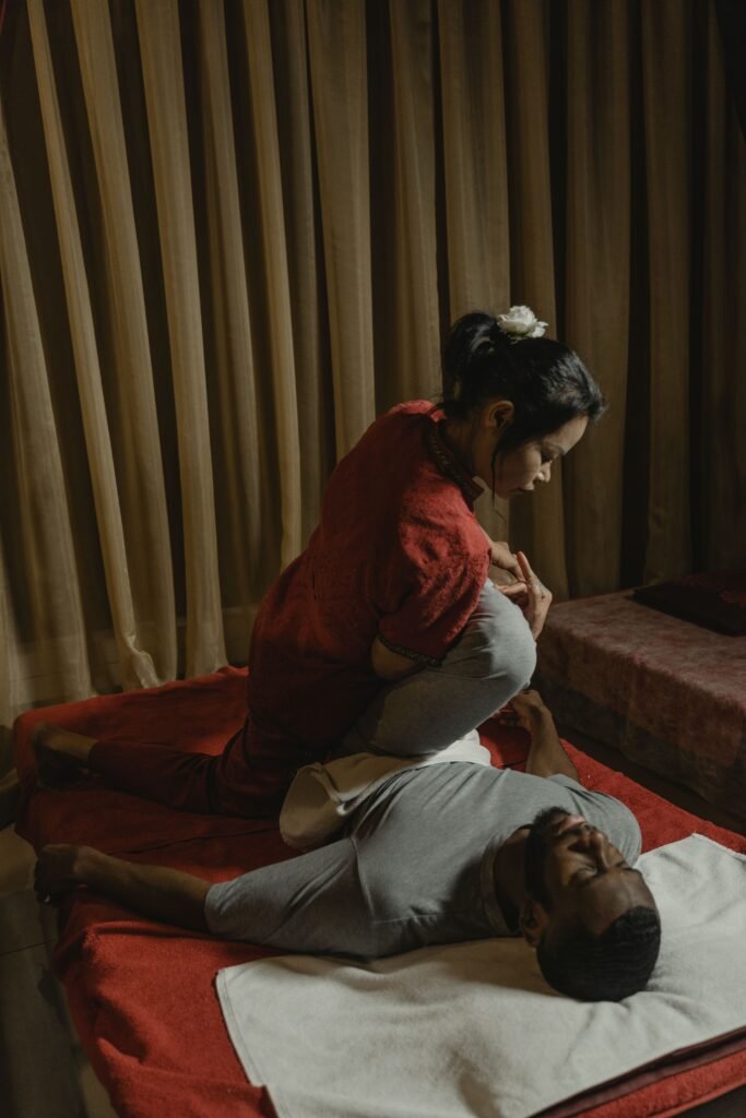 A therapist performs a massage in a dimly lit room, ensuring client relaxation and care.